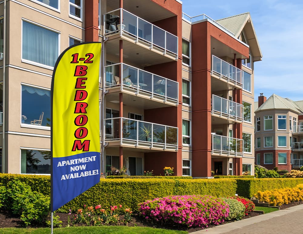 A small yellow feather flag advertising one and two bedroom apartments outside an apartment block