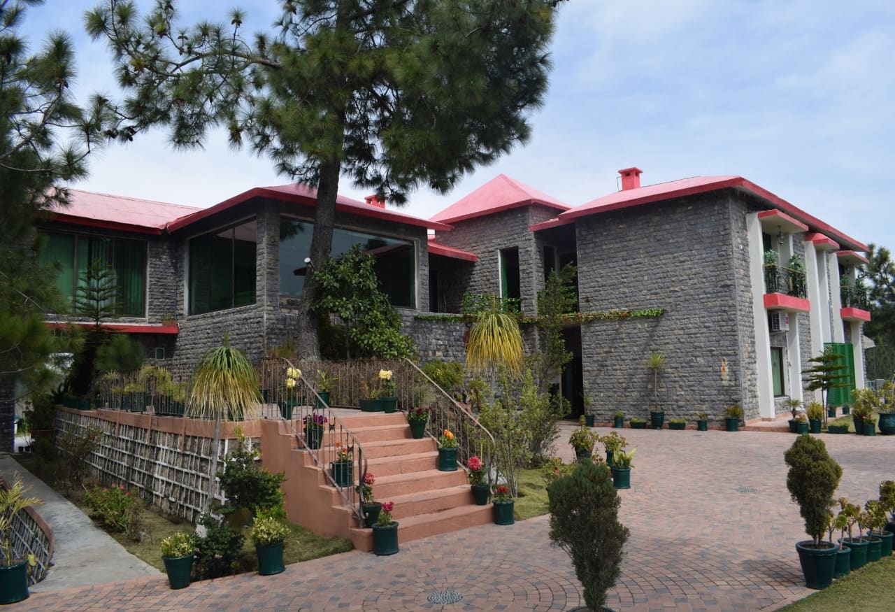 Stone-fronted Marco Polo Resort Abbottabad with a red roof and garden steps