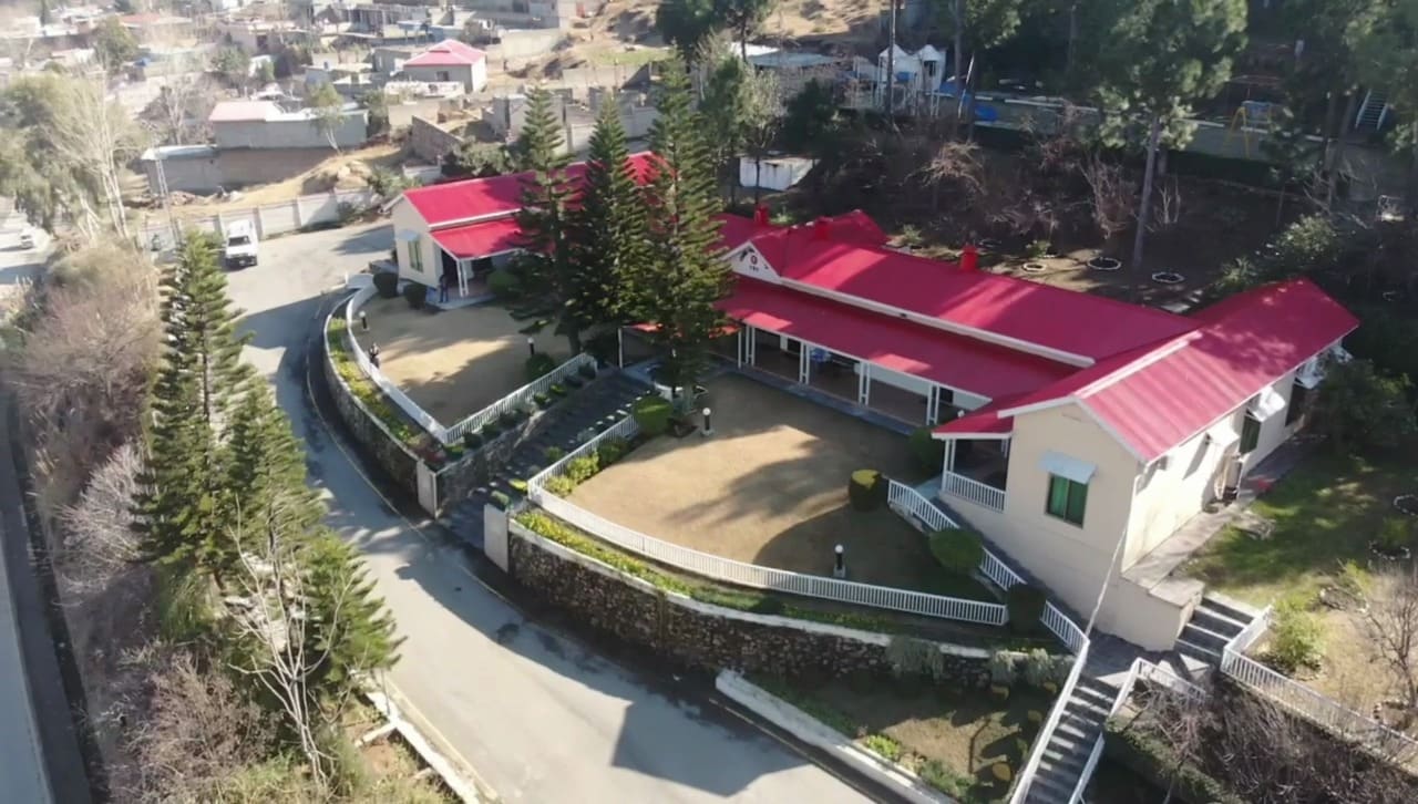 Aerial view of Marco Polo Resort Mansehra with red-roofed buildings among pine trees
