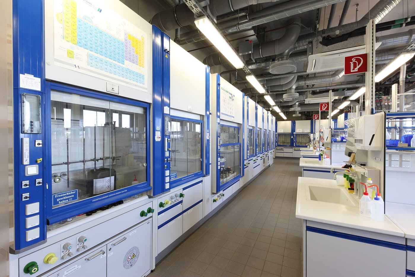 A long chemical laboratory with fume cupboards and workbenches